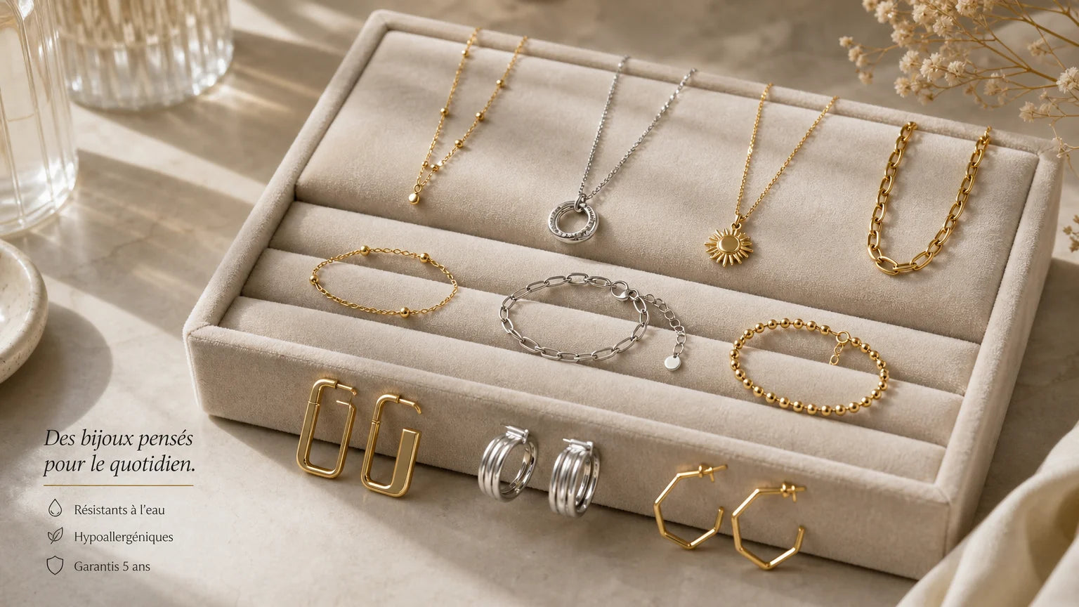 Sélection de bijoux fins en acier et plaqué or sur un plateau clair