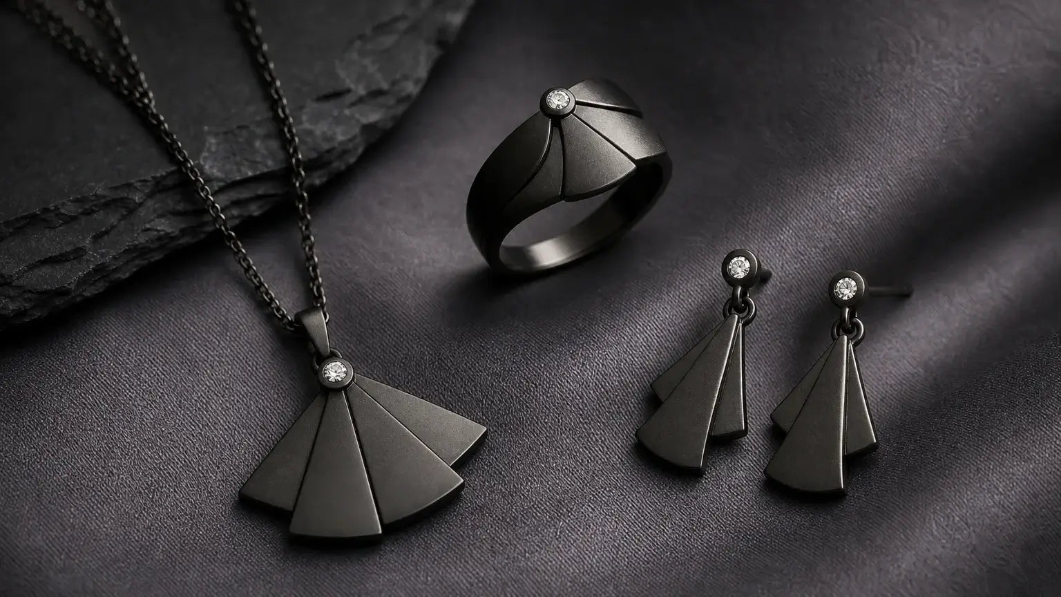 Parure de bijoux en or noir à finition mate sur fond gris anthracite
